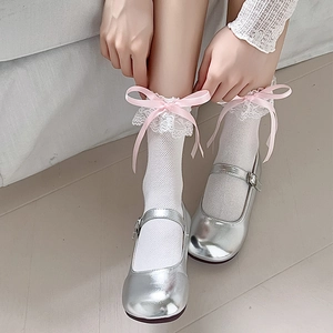 Detail von weißen Spitzensocken mit rosa Schleifen und silbernen Mary Janes