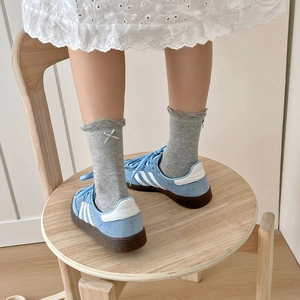 Detail of light blue suede sneakers with classic stripes and grey bow ruffled socks
