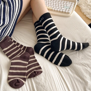 Detail of striped wool socks featuring rib-knit cuffs and delicate letter embroidery