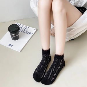 Détail de chaussettes noires à bordure en dentelle avec motif résille pour femme