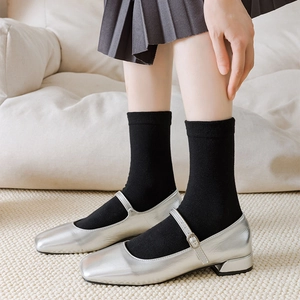 Silver Mary Jane shoes with square toe and black crew socks on textured carpet