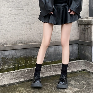 Detail of sheer mesh crew socks in black paired with platform loafers and mini skirt