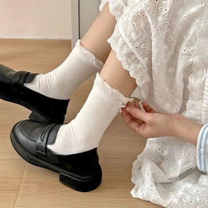 Detail of white mid-calf socks featuring wavy lettuce edges and side bow decorations