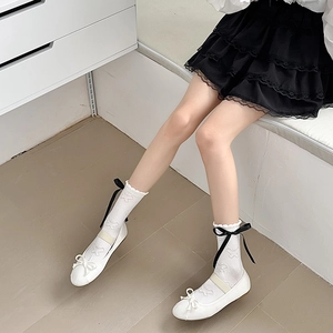Detail of white lace socks with butterfly embroidery and elegant black ribbon ties