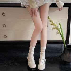 Close-up of off-white platform Mary Jane shoes with mesh socks and retro collegiate style