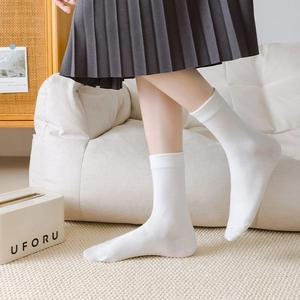 Close-up of white combed cotton mid-calf socks with ribbed cuffs and fine knit texture