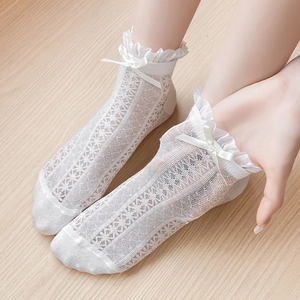 Close-up of white lace mesh socks featuring frilly ruffled cuffs and sweet ribbon bows