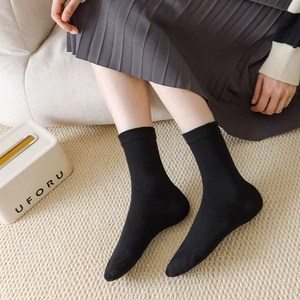 Detailed close-up of soft black cotton knit mid-calf socks with elastic ribbed cuffs
