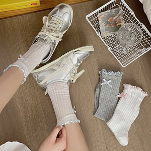 Detail of ruffle cuff socks with bows in white and grey on a wooden background