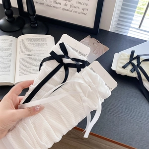 Detail of white ribbed leg warmers with satin bows and aesthetic academic background