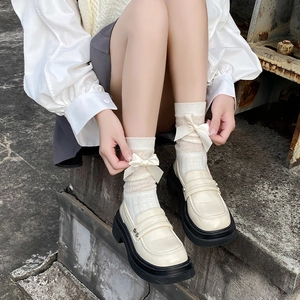 Détail de mocassins crème et chaussettes Lolita avec nœuds amovibles sur pieds
