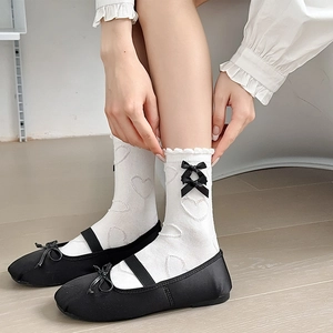 Detailed close-up of white mid-calf socks with black bows and Mary Jane shoes