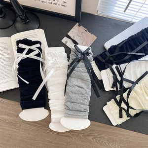Detail of ribbed knit leg warmers with ribbon bows in black, white, and grey tones