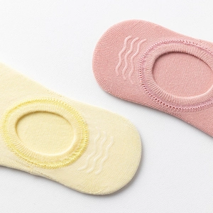 Gros plan de chaussettes basses roses et jaunes avec bandes antidérapantes en silicone