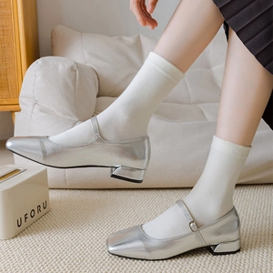 Silver Mary Jane shoes with metallic finish paired with white crew socks in a home setting
