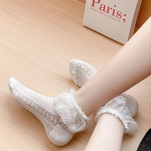 Detailed macro view of white lace mesh socks with delicate frilled edges and hollow patterns