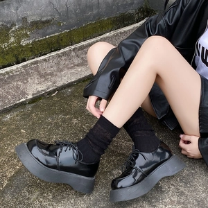 Close-up of black patent leather platform shoes paired with stylish mesh crew socks