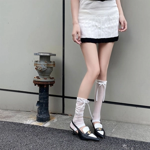 Detail of white striped leg warmers with ribbon bows paired with pointed toe heels