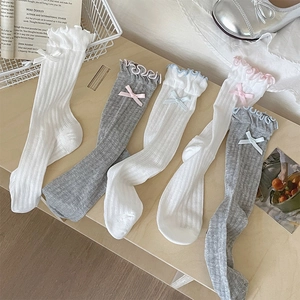 Close-up of ribbed knit socks with ruffled edges and bows on a cozy wooden background