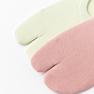 Détail de chaussettes tabi vert clair et rose montrant la texture et le bout fendu