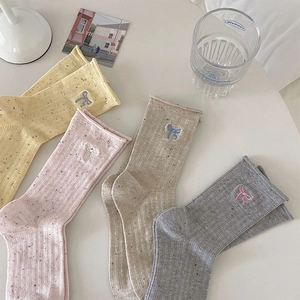 Detailed flat lay of four colorful crew socks with bow embroidery and knitted texture