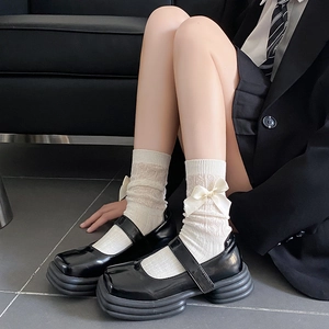 Détail de chaussettes en dentelle crème avec nœud amovible et chaussures Mary Jane noires