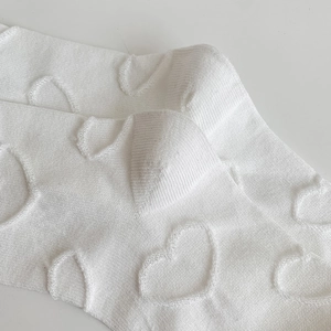 Close-up of white JK socks featuring knitted heart jacquard texture and bubble cuffs