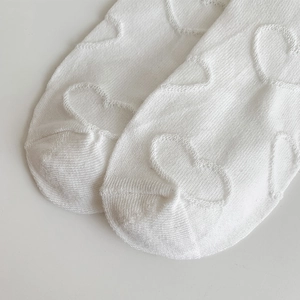 Close-up of white JK style socks with knitted heart texture and soft cotton material