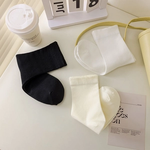 Detailed knit texture of minimalist mid-calf socks in black, white and cream tones