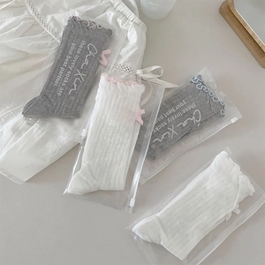 Detail view of cotton mesh crew socks with ruffle trim and bows in zipper packaging