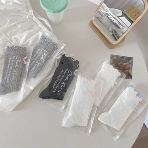 Detailed view of ballet-style mesh socks with lace trim and bow in zip packaging