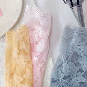 Detailed macro view of delicate floral lace mesh fabric in yellow, pink and blue tones