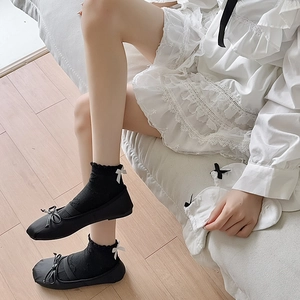 Detail of black JK ruffle socks with white ribbon bows paired with classic black oxfords