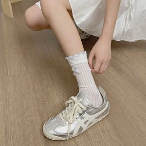 Detail of white mesh socks featuring light blue ruffled edges and a delicate bow detail