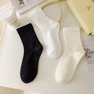 Flat lay of minimalist cotton socks in black, white, and beige with stylish lifestyle props