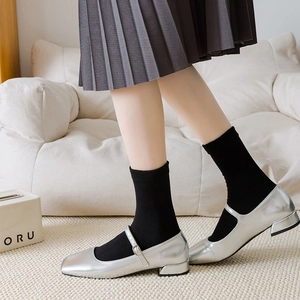 Detail of silver Mary Jane shoes with metallic finish and square toe over black socks