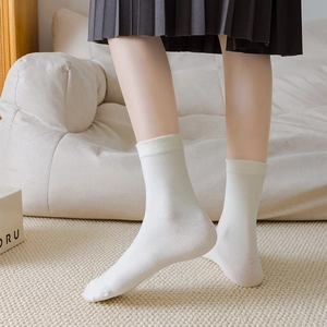 Detail of white cotton mid-calf socks with ribbed cuffs and smooth knitted texture