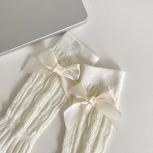 Détail de chaussettes blanches Lolita avec tricot vertical et nœud en satin crème