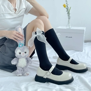 Detail of black calf socks featuring sheer organza bows paired with Mary Jane shoes