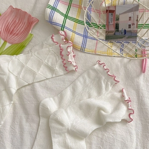 Dettaglio di calze in pizzo bianco con bordi rosa smerlati e trama a rete a rombi