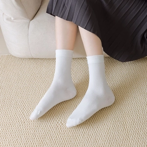 Classic white mid-calf socks for women styled with black skirt in a cozy home setting