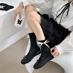 Detail of black JK mid-calf socks with white bow accents and Mary Jane shoes