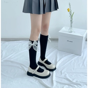 Detail of black knee-high socks with white sheer organza bows and Mary Jane platform shoes