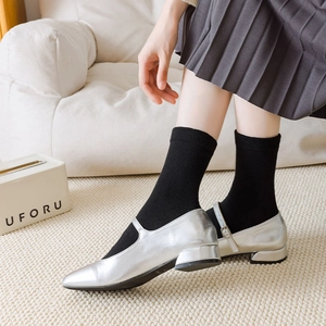 Silver pointed-toe Mary Jane shoes styled with black socks and a pleated skirt