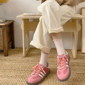 Pink suede sneakers with frilly dot socks and corduroy pants in a cozy indoor setting