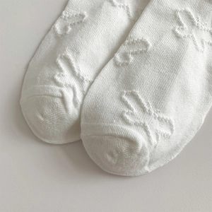 Detailed macro view of white knit socks with fine butterfly jacquard and bow texture