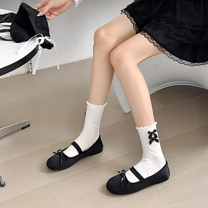 Detailed view of white JK socks with black satin bows and delicate heart jacquard pattern