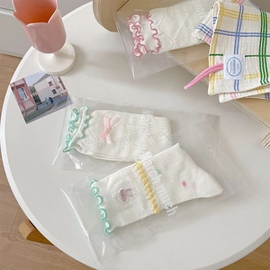 Dettaglio calzini con pizzo dolce, motivi a fragola e decorazioni con fiocchi rosa