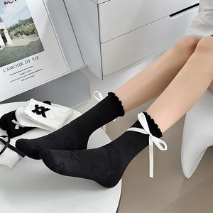 Detail view of black Balletcore socks featuring white ribbon bows and lace trim on the cuff