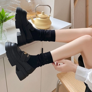 Close-up of black leather platform loafers with gold metal buckle and black crew socks